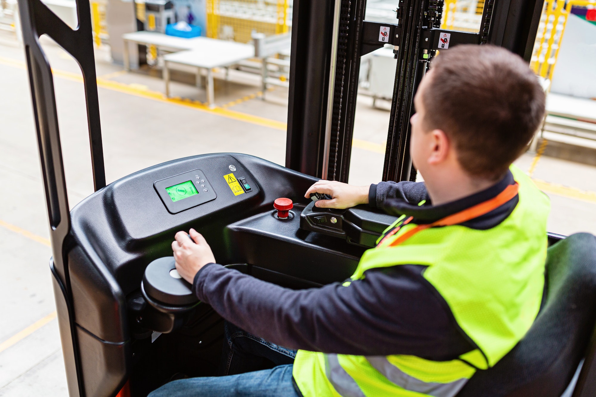 Storehouse employee in uniform working on reachtruck in modern automatic warehouse.