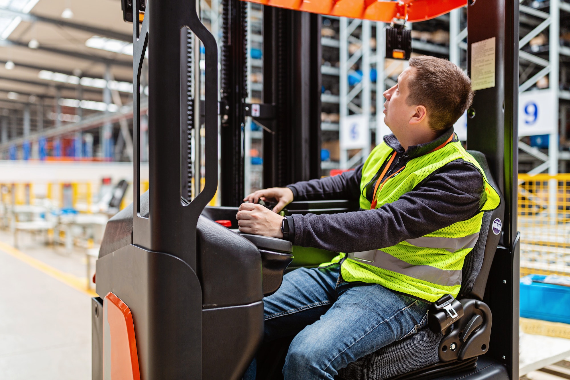 Storehouse employee in uniform working on reachtruck in modern automatic warehouse.